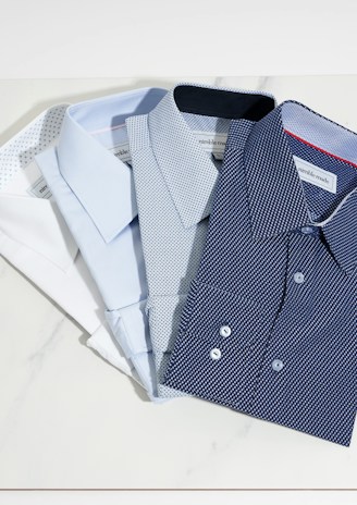 Close-up of soft, breathable cotton dress shirts neatly folded on a wooden table.
