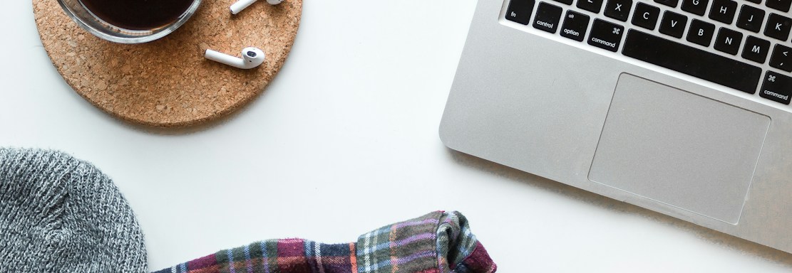 A clean, minimalist workspace with a tailored suit neatly hung beside a laptop and a cup of coffee.