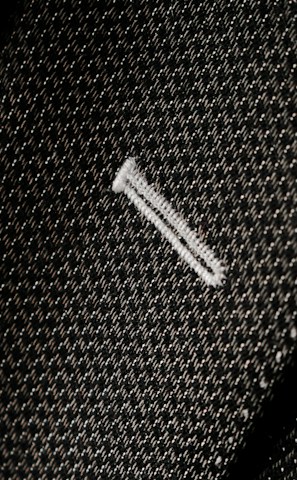 Close-up of a finely stitched lapel on a charcoal gray suit jacket.