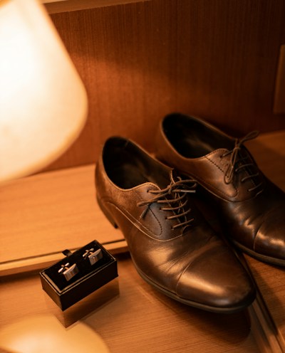 A pair of classic leather dress shoes polished to a shine on a rustic floor.