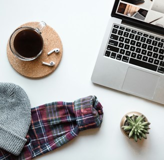 A clean, minimalist workspace with a tailored suit neatly hung beside a laptop and a cup of coffee.
