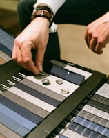 Hands selecting soft, high-quality fabric swatches in warm, neutral tones.